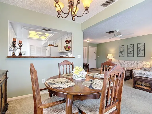Dining space with carpet floors, a chandelier, a textured ceiling, and a ceiling fan