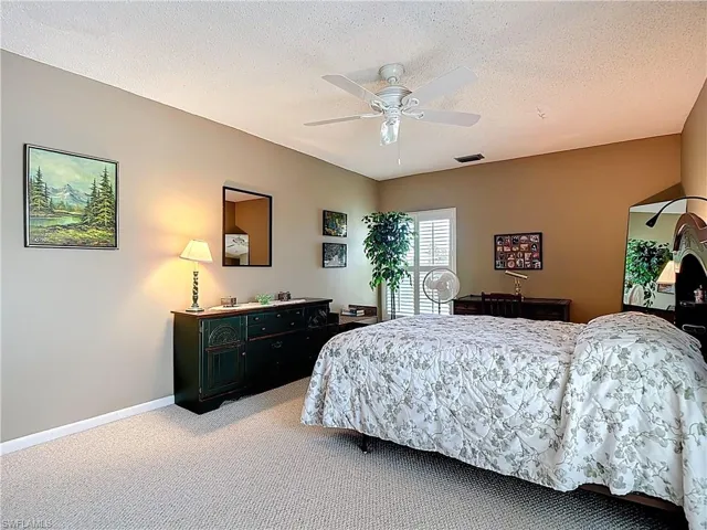 Bedroom with light colored carpet, a textured ceiling, and a ceiling fan
