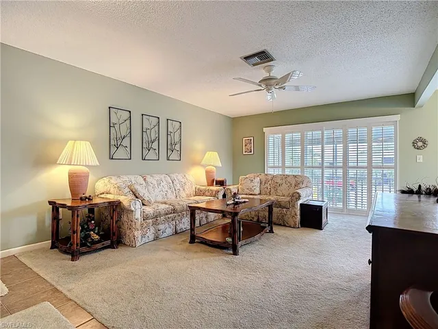 Living room featuring a textured ceiling, ceiling fan, and light tile patterned flooring