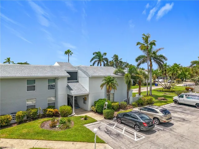View of property with stairway and uncovered parking