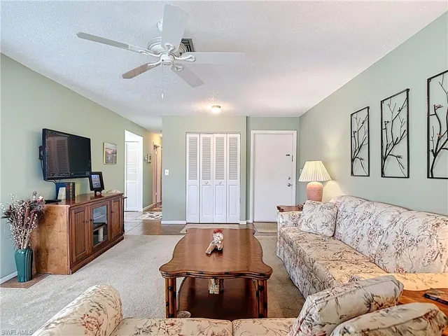 Carpeted living area featuring a textured ceiling and baseboards
