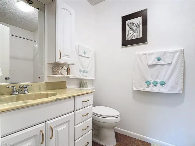 Bathroom with a shower, vanity, a textured ceiling, and dark tile patterned flooring