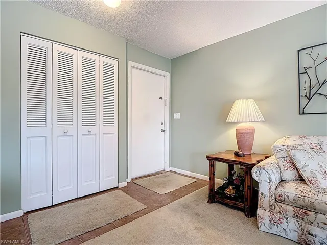 Carpeted foyer entrance with a textured ceiling and baseboards