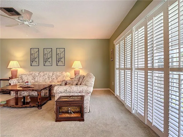 Carpeted living room with a ceiling fan and a textured ceiling