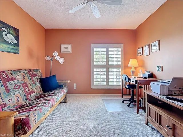 Carpeted office with a textured ceiling and ceiling fan
