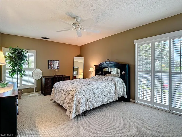 Carpeted bedroom with a textured ceiling and ceiling fan