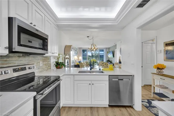 Kitchen with stainless steel appliances, light wood-style floors, white cabinets