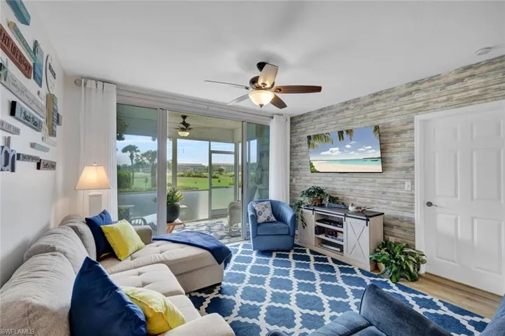Living area featuring wood finished floors, an accent wall, and a ceiling fan