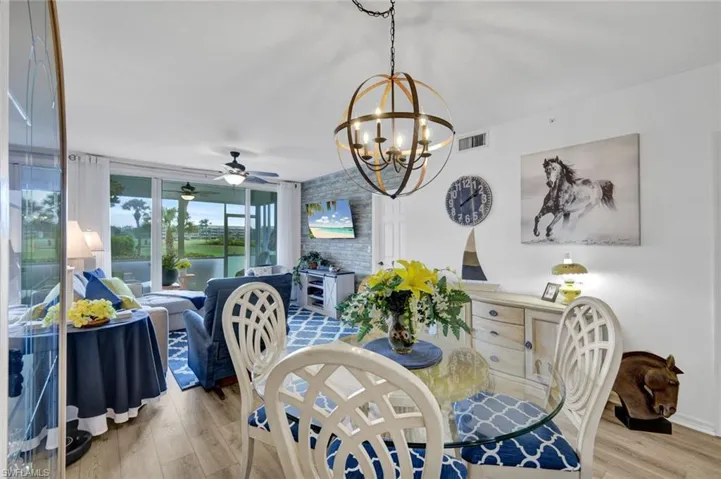 Dining area with a ceiling fan, light wood-type flooring, and suspended lighting