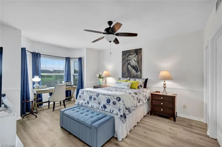 Bedroom with bay impact-windows, light wood finished floors and ceiling fan