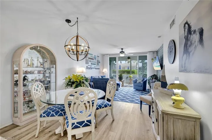 Dining room with ceiling fan, hanging lights, and light wood-style floors