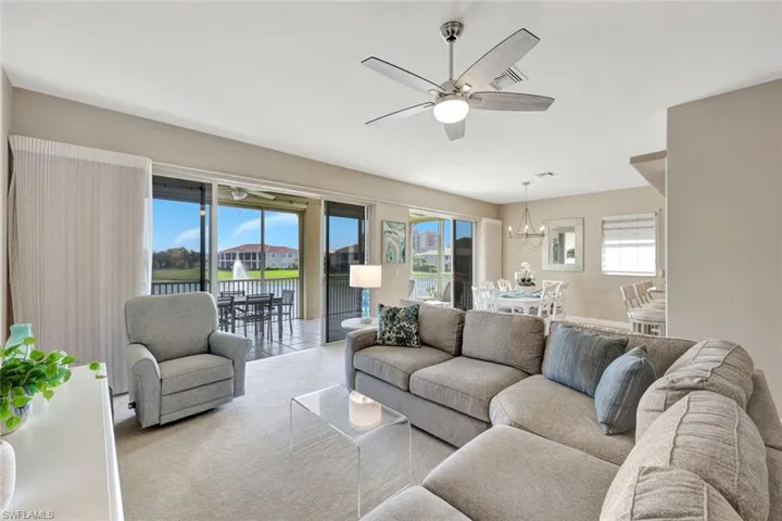 Carpeted living room with a water view, plenty of natural light, ceiling fan, and a chandelier