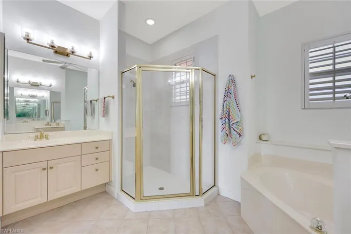 Full bathroom with a shower stall, vanity, a garden tub, and light tile patterned floors