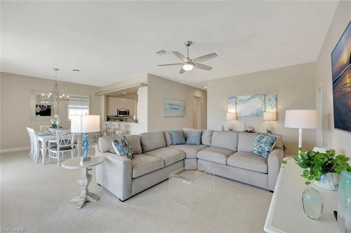 Carpeted living area featuring a ceiling fan and a chandelier