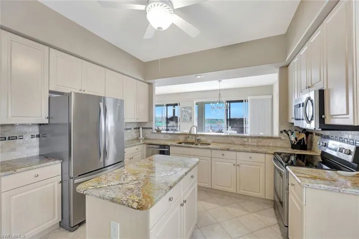 Kitchen featuring appliances with stainless steel finishes, tasteful backsplash, a chandelier, and light stone counters