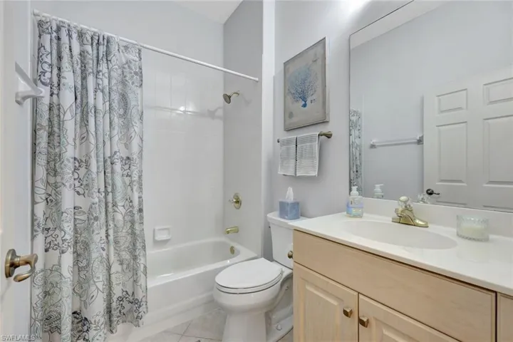 Full bathroom with shower / bath combo with shower curtain, vanity, and light tile patterned floors