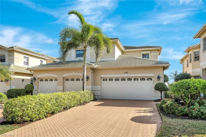 Traditional-style home with decorative driveway, a tiled roof, and stucco siding