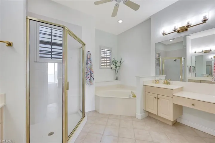 Full bathroom featuring vanity, a garden tub, a shower stall, light tile patterned flooring, and ceiling fan