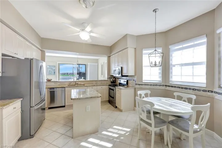 Kitchen with a chandelier, decorative light fixtures, stainless steel appliances, light stone countertops, and a center island