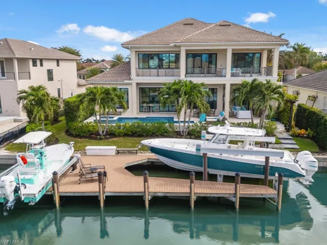 Back of house featuring a water view, a balcony, a patio, and a pool