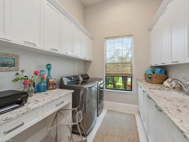 Laundry room with cabinets, light tile patterned floors, washer and clothes dryer, and sink