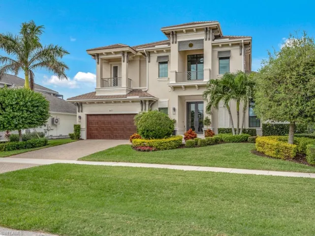 View of front of home featuring a garage, a balcony, and a front lawn
