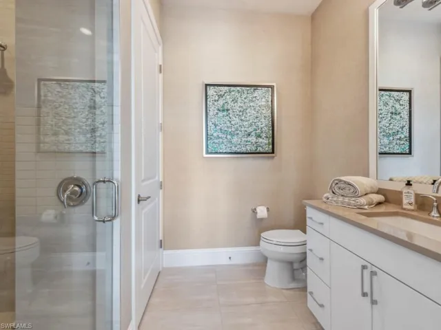 Bathroom with walk in shower, tile patterned flooring, vanity, and toilet