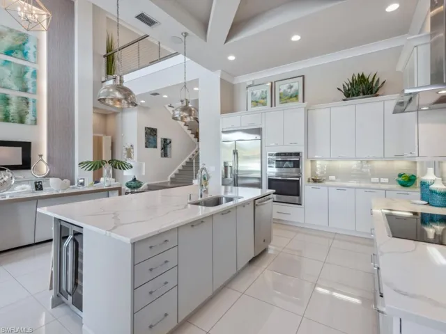 Kitchen featuring a center island with sink, decorative light fixtures, white cabinetry, and sink