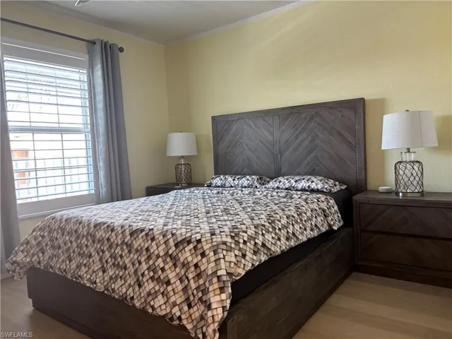Bedroom with wood finished floors and crown molding