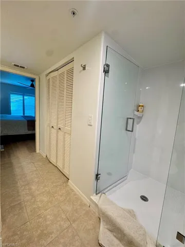 Master bathroom featuring a closet, a shower stall, and light tile patterned floors