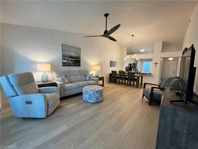 Living room featuring lofted ceiling, ceiling fan, light wood finished floors and open to dining room