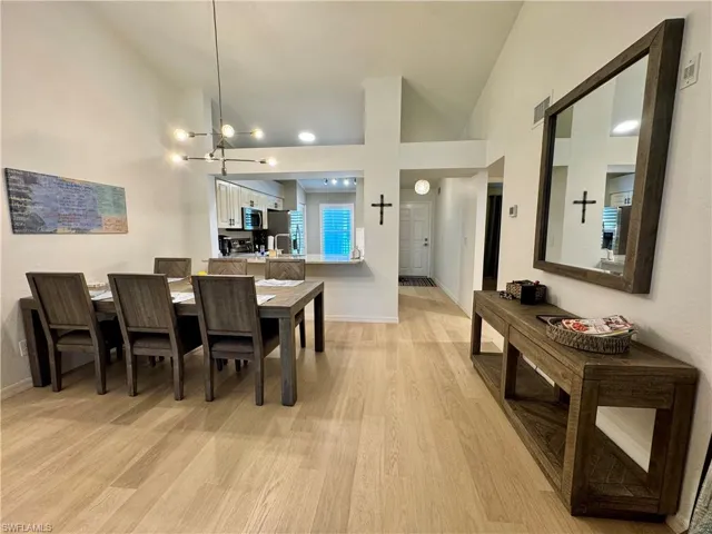 Dining room featuring vaulted ceiling, light wood finished floors, and a chandelier