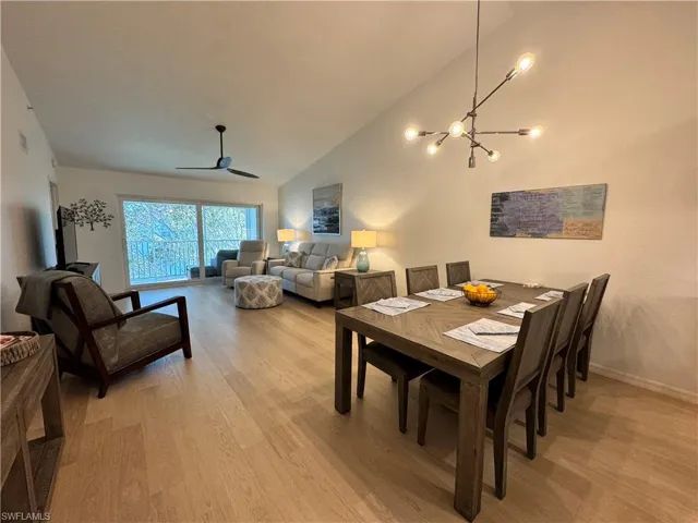 Dining room featuring vaulted ceiling, light wood-style flooring, a chandelier, and ceiling fan