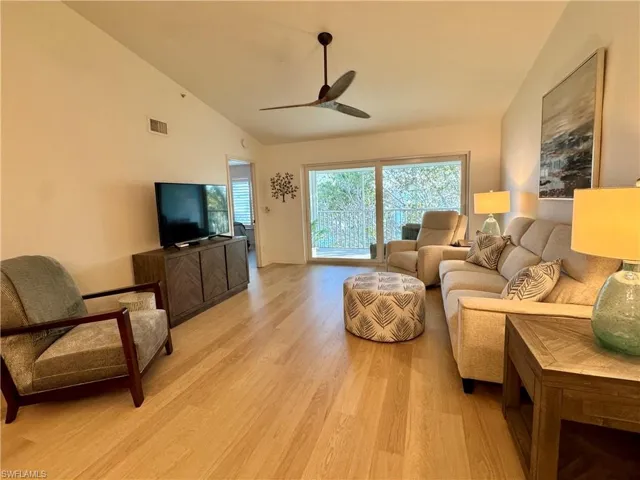 Living room featuring vaulted ceiling, light wood finished floors, and a ceiling fan