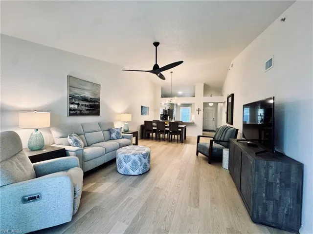 Living room with Luxury vinyl light wood-style floors, lofted ceiling, and ceiling fan