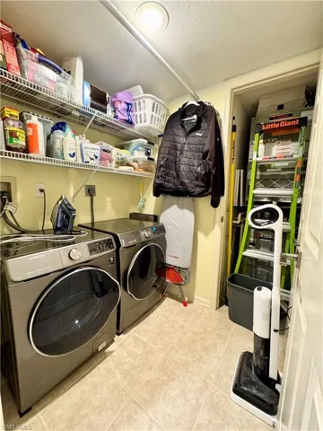 Laundry room with a textured ceiling, independent washer and dryer, and light tile patterned floors