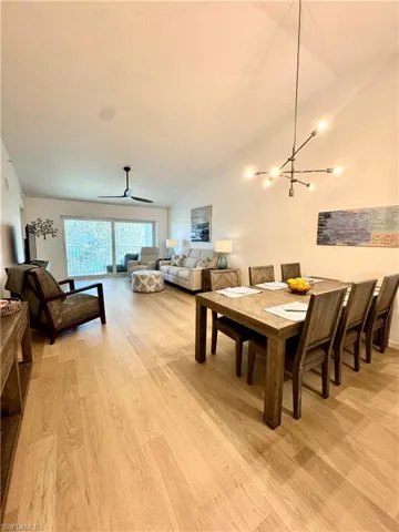 Dining room featuring light wood-style flooring, vaulted ceiling, a ceiling fan, and a chandelier
