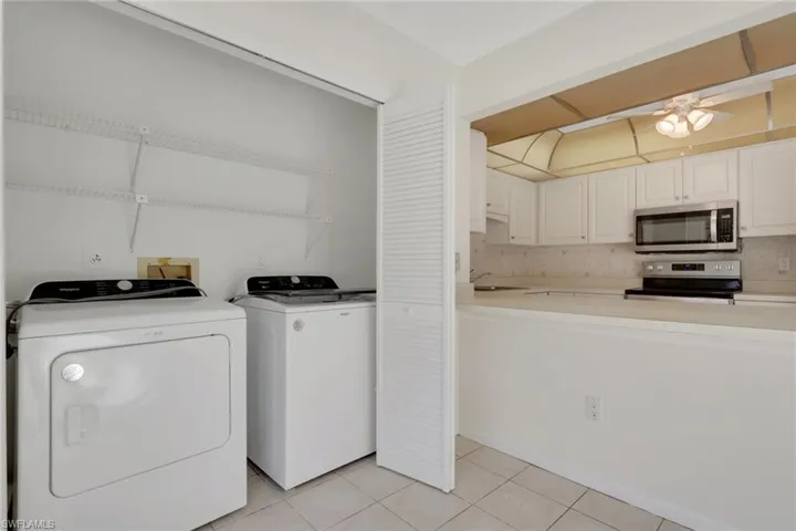 Laundry room with washer and clothes dryer, light tile patterned floors, and a ceiling fan