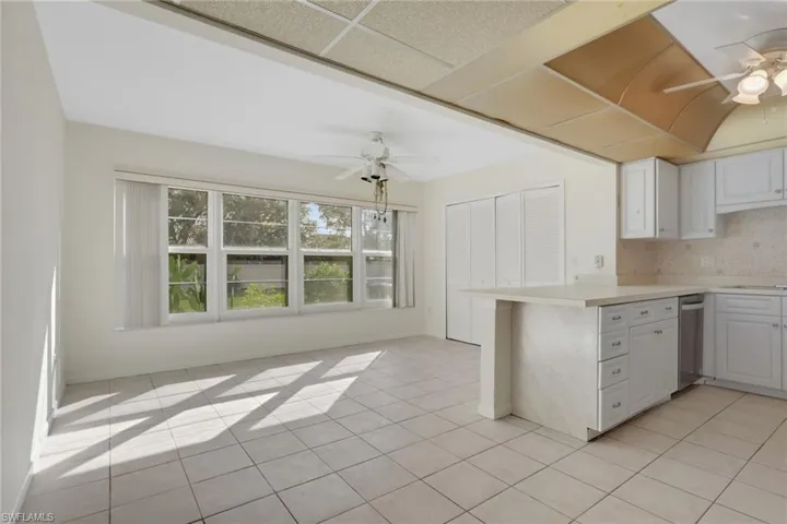 Kitchen featuring ceiling fan, white cabinets, decorative backsplash, light countertops, and a drop ceiling