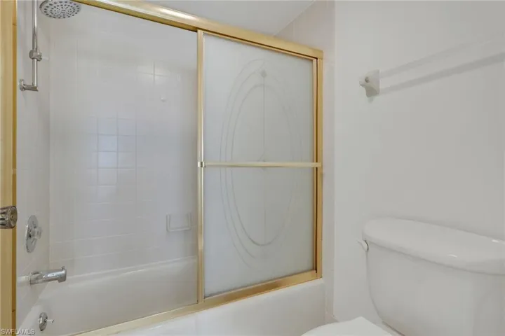 Bathroom featuring toilet and enclosed tub / shower combo