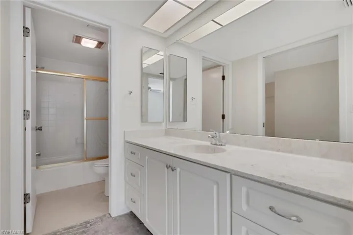 Bathroom with bath / shower combo with glass door and vanity