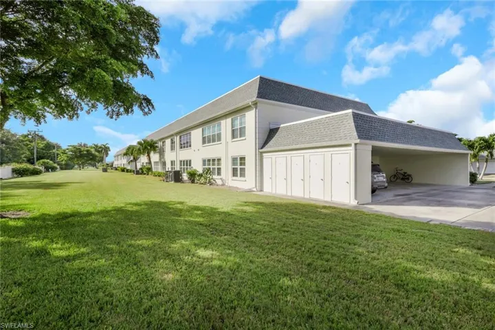 View of property exterior featuring roof with shingles, a yard, an attached carport, and concrete driveway