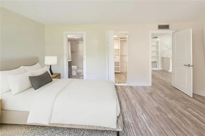 Bedroom featuring wood finished floors, a walk in closet, and ensuite bath