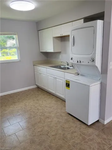Laundry area featuring stacked washer and clothes dryer and cabinet space