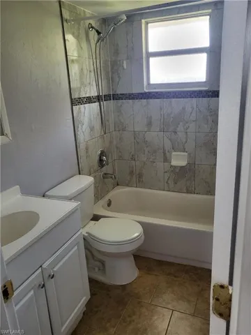 Full bath featuring vanity, a textured wall, and bathing tub / shower combination