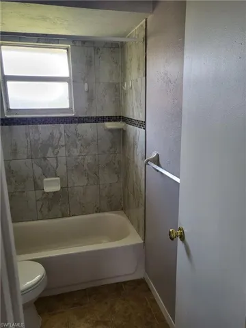Full bath featuring a textured wall and shower / bath combination