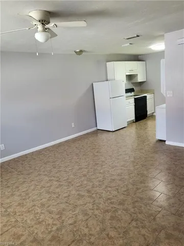 Kitchen featuring white cabinetry, freestanding refrigerator, electric stove, light countertops, and ceiling fan