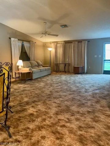 Unfurnished living room featuring carpet floors and ceiling fan