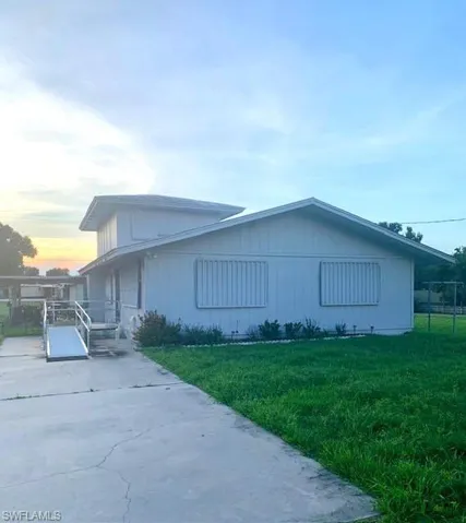 Property exterior at dusk with a patio and a lawn