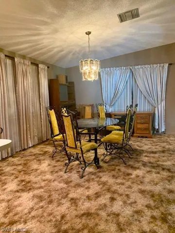 Dining space with an inviting chandelier, carpet, and a textured ceiling